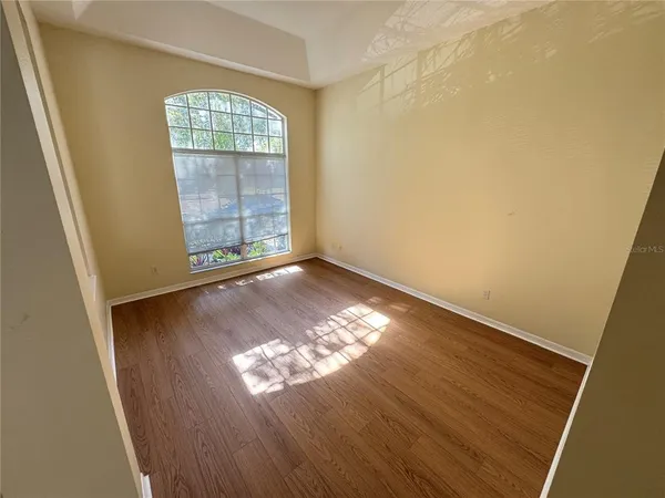 a view of an empty room with wooden floor and a window