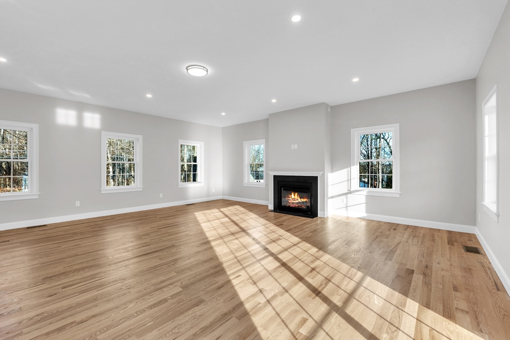 116 Townsend Harbor Road Lunenburg, MA 01462 - Photo 12 of 30 an empty room with wooden floor fireplace and windows