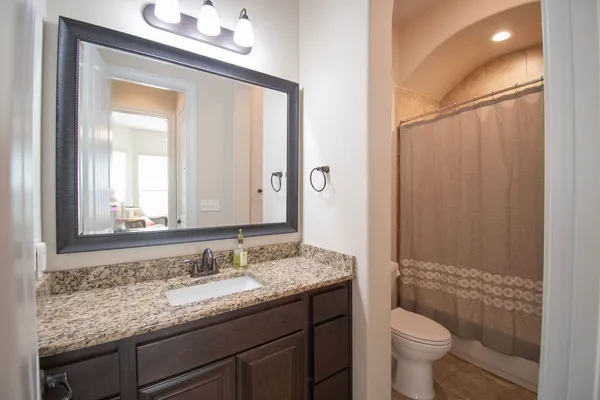 a bathroom with a granite countertop sink toilet and mirror