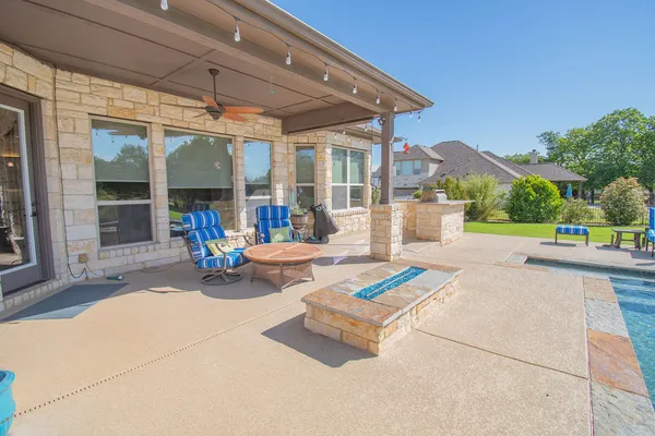 a view of a patio with a table and chairs under an umbrella with a small yard