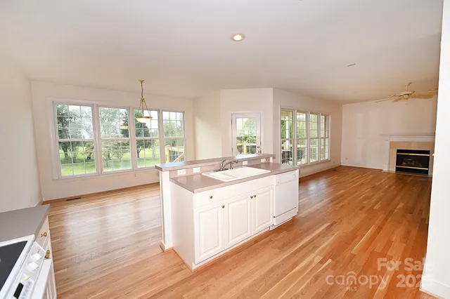 a large white kitchen with wooden floor and a window