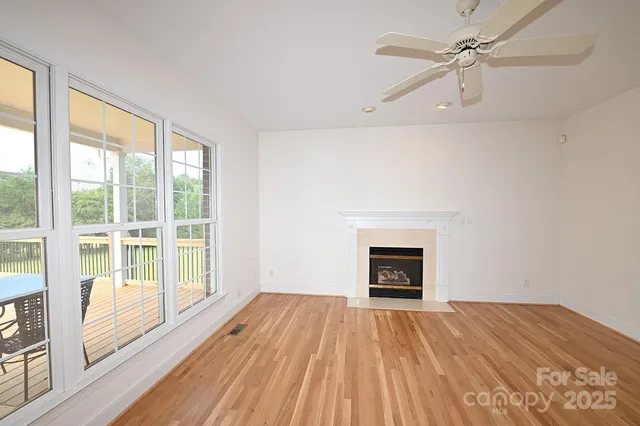 an empty room with wooden floor a ceiling fan and windows