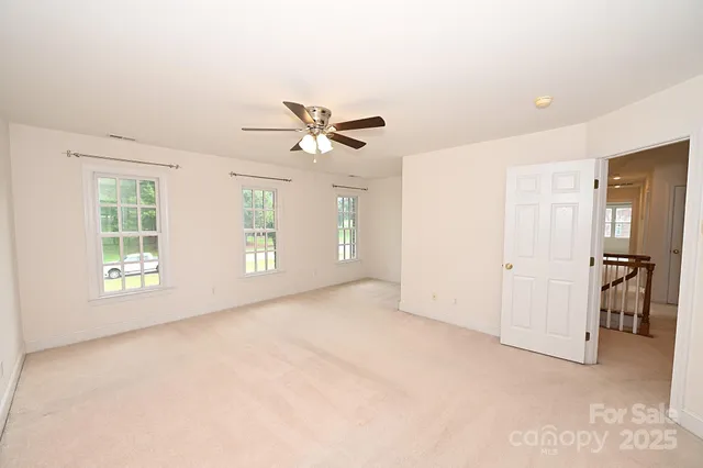 an empty room with windows and ceiling fan