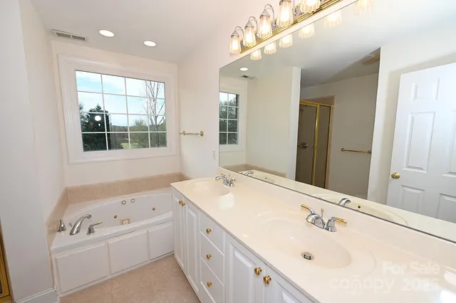a bathroom with a tub sink double vanity and windows