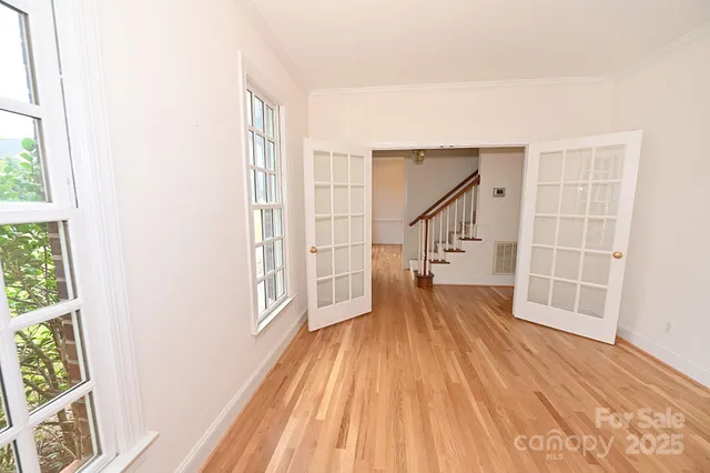 an empty room with wooden floor and windows