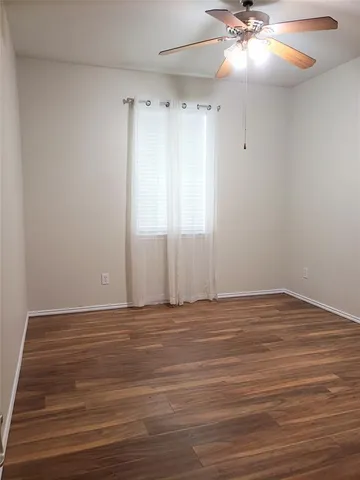 a view of an empty room with window and wooden floor