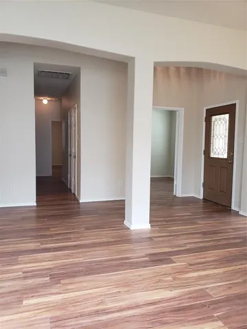 a view of an empty room with wooden floor and closet