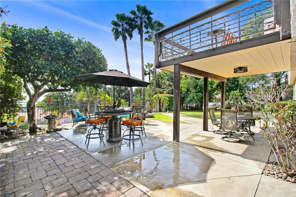 a view of a patio with a table and chairs under an umbrella with a small yard