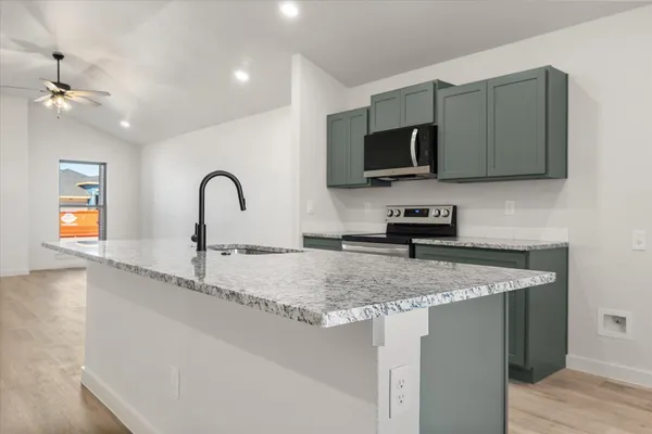 a kitchen with stainless steel appliances granite countertop a sink dishwasher a microwave oven and a refrigerator with wooden cabinets