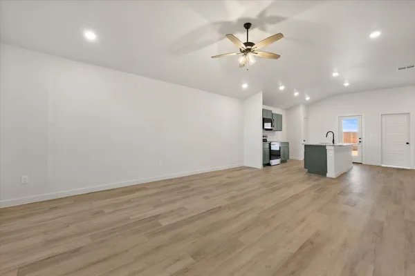 a view of an empty room with a ceiling fan window and wooden floor
