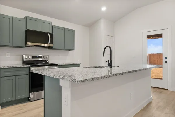 a kitchen with stainless steel appliances granite countertop a sink and a stove top oven with wooden floor