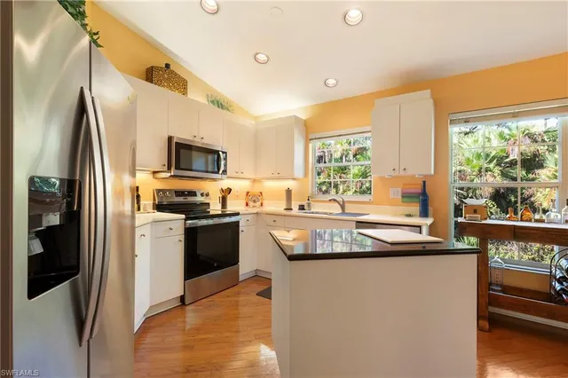 a kitchen with stainless steel appliances granite countertop a refrigerator a stove top oven a sink and dishwasher