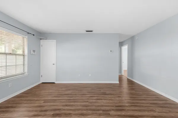 a view of an empty room with wooden floor and a window