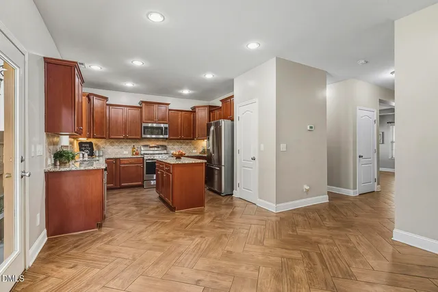 a large kitchen with stainless steel appliances granite countertop a stove top oven a sink dishwasher and white cabinets
