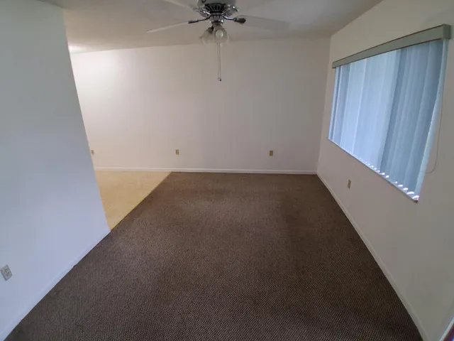 an empty room with a ceiling fan and a window