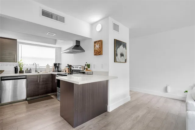 a kitchen with stainless steel appliances granite countertop a refrigerator a sink dishwasher a stove with white cabinets and wooden floor