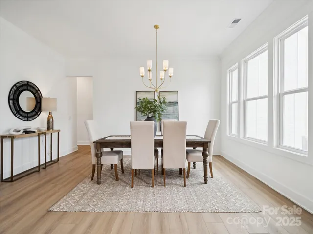 a dining room with wooden floor a chandelier a wooden table and chairs