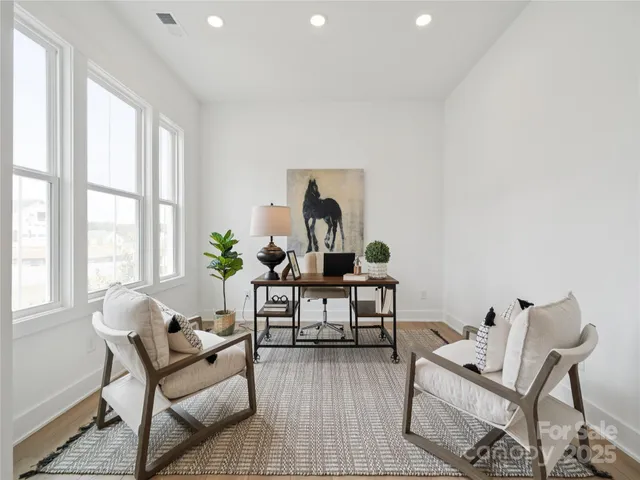 a living room with furniture a rug potted plant and a window