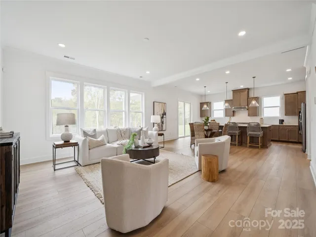a living room with lots of furniture wooden floor and a large window