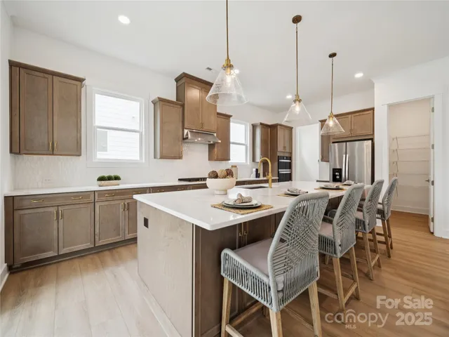 a kitchen with a dining table chairs sink and wooden floor