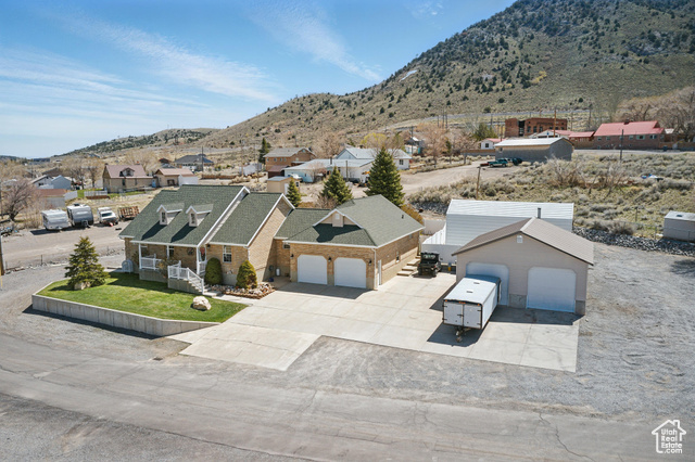 151 South Haulage Road Eureka, UT 84628 - Photo 4 of 36 View of front facade with driveway, a mountain view, a garage, brick siding, and a shingled roof