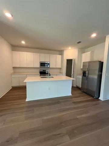 a large kitchen with stainless steel appliances kitchen island granite countertop a stove a refrigerator a sink and a white cabinets