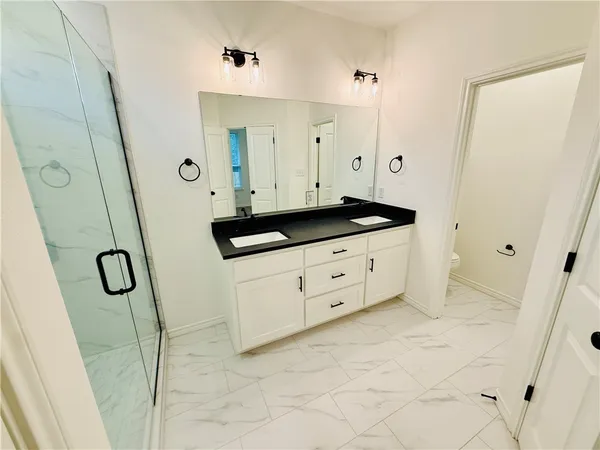 a bathroom with a granite countertop sink a mirror a vanity and a shower