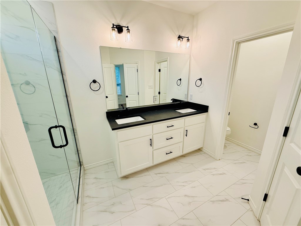 1202 Suncrest Street Bryan, TX 77803 - Photo 13 of 21 a bathroom with a granite countertop sink a mirror a vanity and a shower