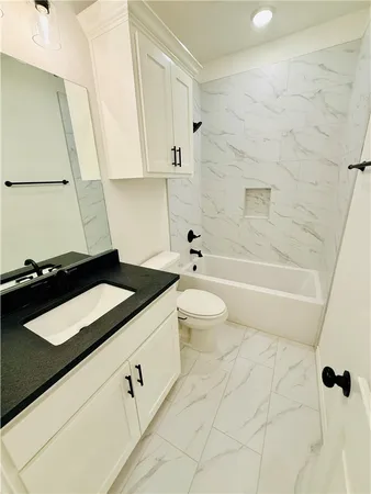 a bathroom with a granite countertop sink a toilet and bathtub