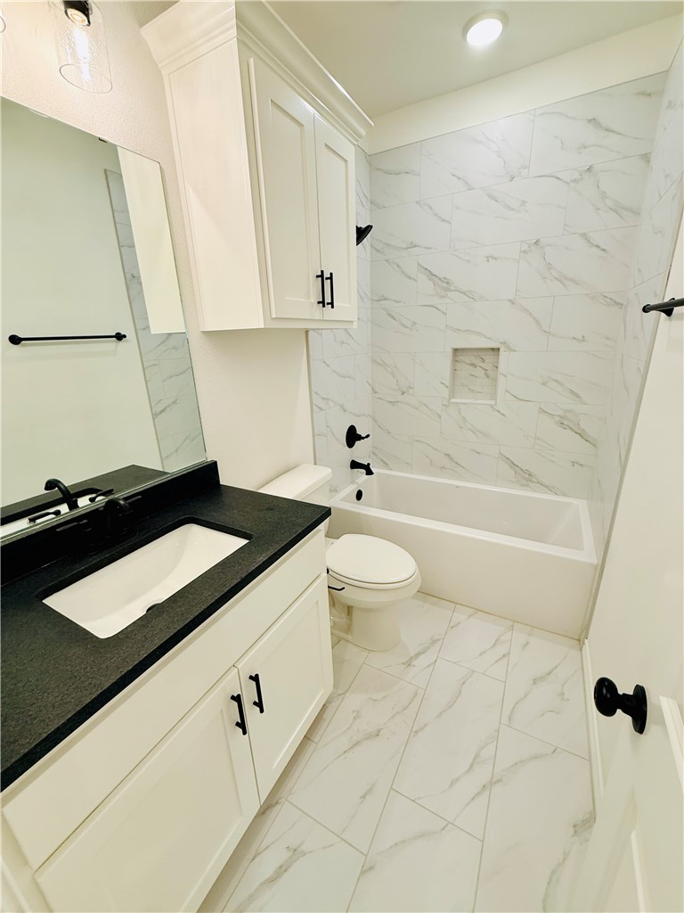 1202 Suncrest Street Bryan, TX 77803 - Photo 16 of 21 a bathroom with a granite countertop sink a toilet and bathtub