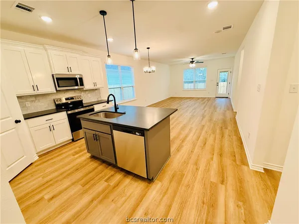 a kitchen with stainless steel appliances granite countertop a sink a stove and a wooden floors
