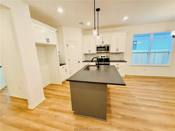 a kitchen with stainless steel appliances granite countertop a sink a stove and a refrigerator