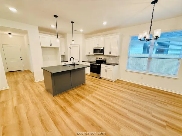 a kitchen with stainless steel appliances kitchen island granite countertop a sink and a refrigerator