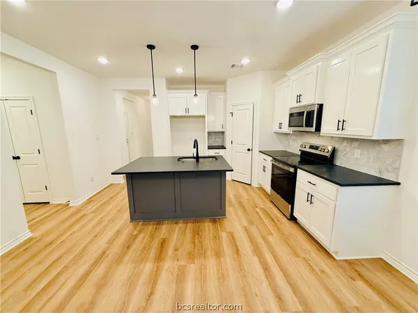 a large kitchen with stainless steel appliances granite countertop a sink a stove counter space and cabinets