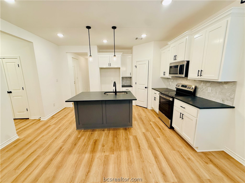 1202 Suncrest Street Bryan, TX 77803 - Photo 6 of 21 a large kitchen with stainless steel appliances granite countertop a sink a stove counter space and cabinets