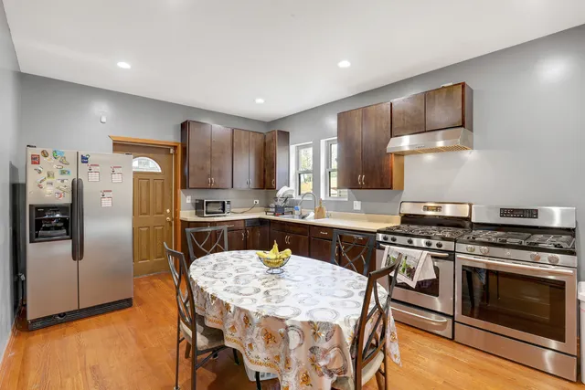 a kitchen with stainless steel appliances a stove a sink dishwasher a refrigerator with a dining table and chairs