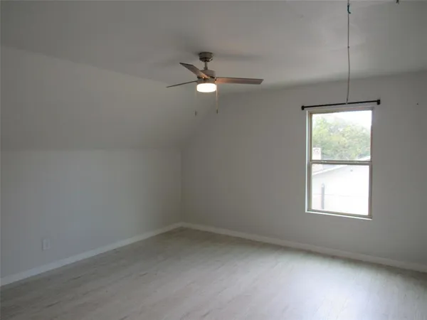 an empty room with a window and ceiling fan