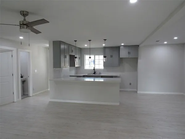 a large kitchen with granite countertop a large counter top a sink stainless steel appliances and cabinets