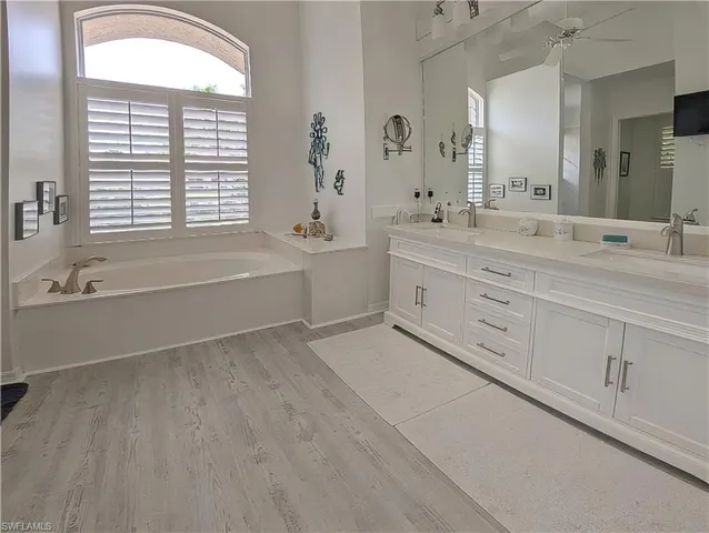 a spacious bathroom with a double vanity sink a mirror and a bathtub