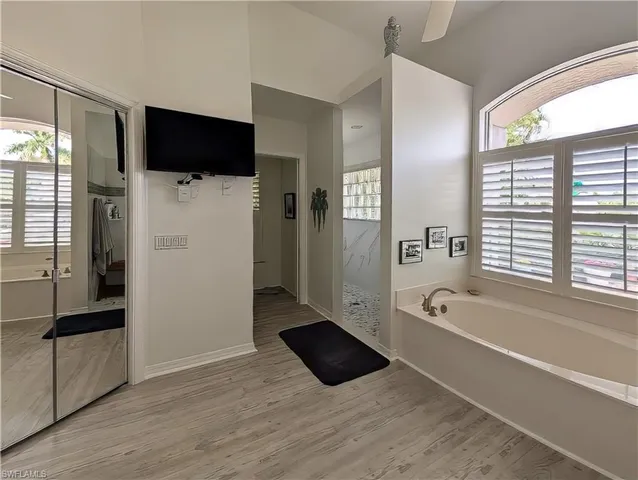 a bathroom with a tub shower and a mirror