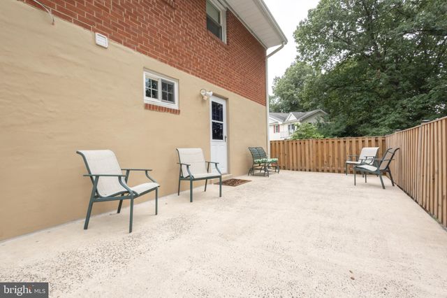a view of a white house next to a yard with big trees