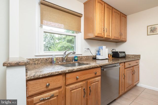 a kitchen with granite countertop stainless steel appliances white cabinets sink and a window