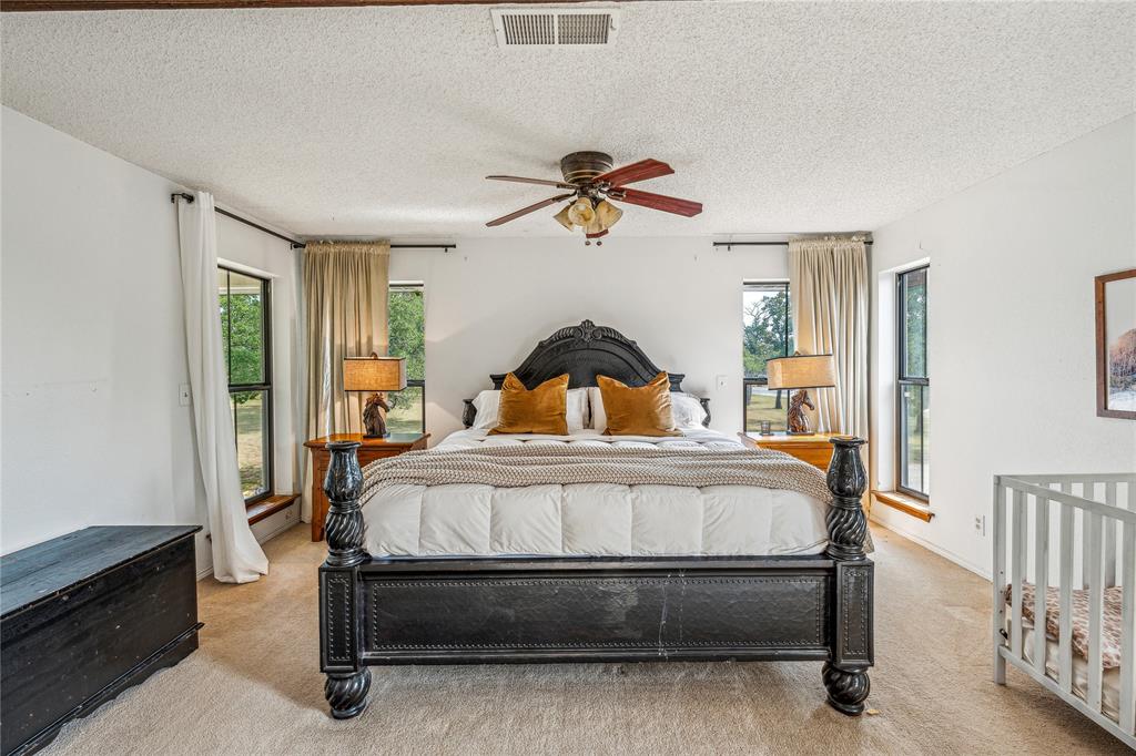 3113 Rock Creek Road Mineral Wells, TX 76067 - Photo 19 of 37 a bedroom with a bed and a chandelier