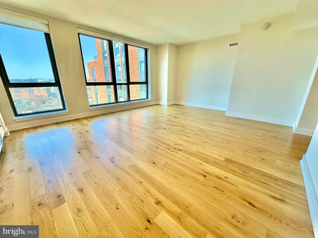 a view of an empty room with wooden floor and windows
