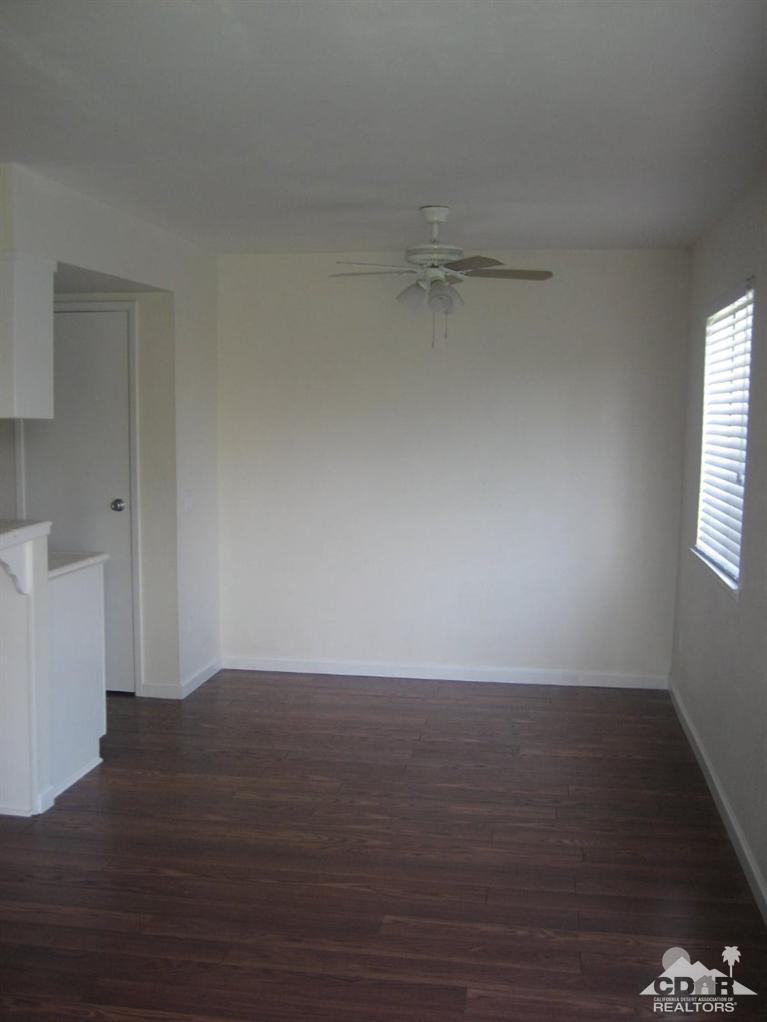 72694 Eagle Road, Unit 3 Palm Desert, CA 92260 - Photo 3 of 35 a view of an empty room with wooden floor and a window