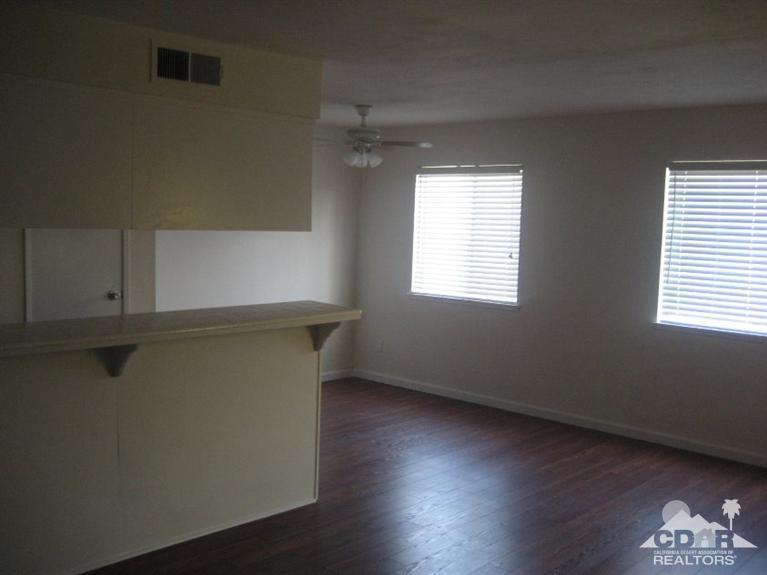 72694 Eagle Road, Unit 3 Palm Desert, CA 92260 - Photo 5 of 35 a view of an empty room with wooden floor and a window