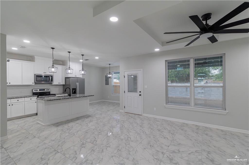 5510 North Crown Point Pharr, TX 78577 - Photo 4 of 14 a large white kitchen with stainless steel appliances granite countertop a stove a sink a refrigerator with white cabinets and wooden floor