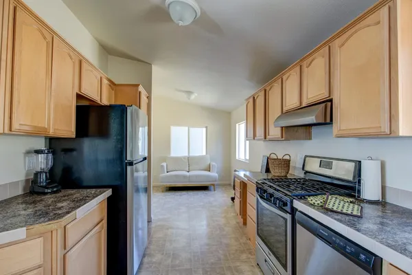 a kitchen with stainless steel appliances granite countertop a stove top oven a sink a dining table and chairs with white cabinets