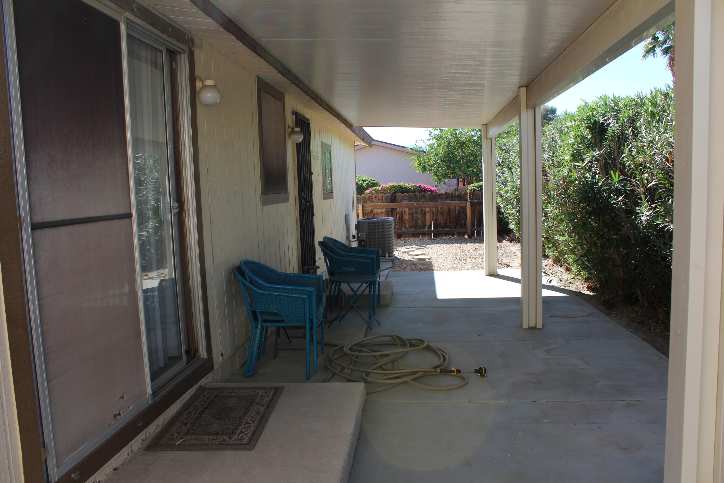 81641 Ave 48, Unit 95 Indio, CA 92201 - Photo 22 of 25 a view of a patio with table and chairs potted plants with floor to ceiling window