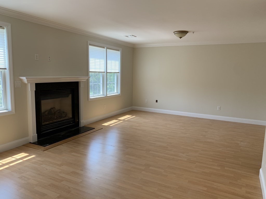 3 Dansereau Place, Unit 3 Middleton, MA 01949 - Photo 5 of 34 a view of empty room with wooden floor and fireplace